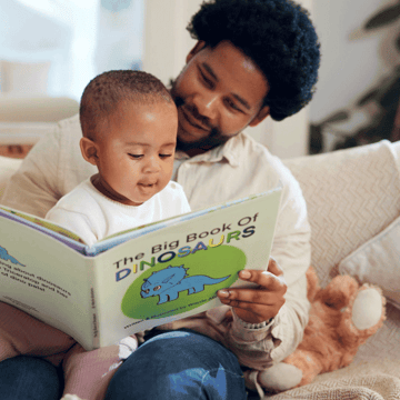 Father and son reading a book together at home in Houston